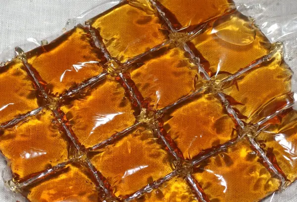 Eiswürfelbeutel sind mit einer goldbraunen Flüssigkeit gefüllt, die wie Tee aussieht, auf einem hellen Hintergrund angeordnet.