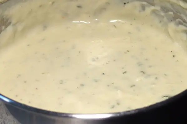 Eine cremige Blauschimmelkäse-Sauce kocht in einem Topf, umgeben von einer modernen Küchenumgebung.