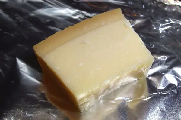 Ein Stück Parmesan-Käse liegt auf Alufolie und wartet darauf, für eine Mahlzeit verwendet zu werden.