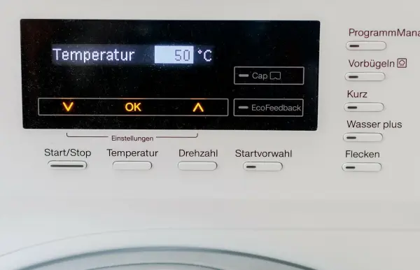 Ein Waschmaschinenanzeigendisplay zeigt die Temperatur von 50 Grad Celsius an. Die Umgebung ist technisch und modern.