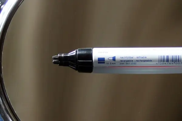 Ein Edding-Marker wird in einem Spiegel betrachtet, der glänzende Oberfläche reflektiert den Stift.