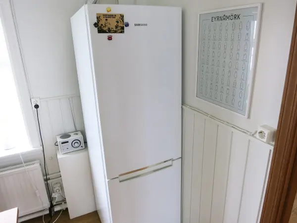 Ein Kühlschrank steht in einer modernen Küche, auf seiner Tür sind Notizen und eine Übersicht angebracht für die Nutzung als Whiteboard.