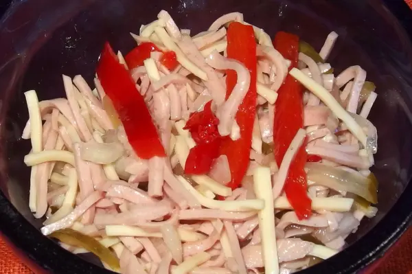 Ein bunter Schwäbischer Wurstsalat liegt in einer Schale, gefüllt mit feinen Wurststücken und roten Paprika.