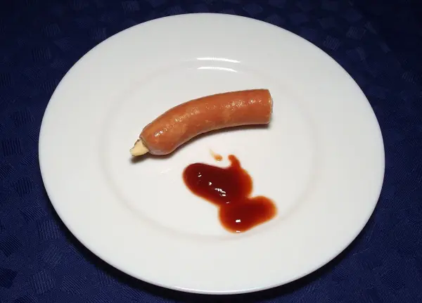 Ein auf einem Teller liegender Wurstfinger mit Ketchup, der auf den ersten Blick wie ein abgehackter Finger aussieht.