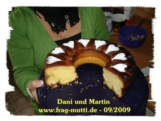Ein Eierlikörkuchen wird von einer Person gehalten, während sie ihn stolz in einer Küche präsentiert.