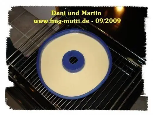 Ein runder Eierlikörkuchen befindet sich auf einem Backrost im Ofen, umgeben von einem glänzenden, dunklen Raum.