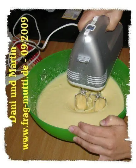 Ein Handmixer verrührt Eierlikörkuchen-Teig in einer grünen Schüssel. Text: "Dani und Martin www.frag-mutti.de - 09/2009".