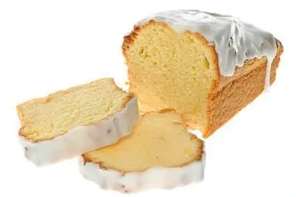 Kuchen mit heller Glasur, angeschnitten, zwei Scheiben abgelegt; auf weißem Hintergrund.