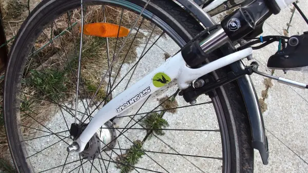 Ein Fahrrad steht auf dem Boden, während es vor Rost geschützt wird. Es ist sonnig und die Umgebung ist grün.