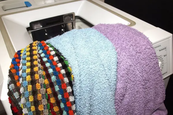 Bunte Handtücher werden in eine Waschmaschine gelegt, um sie im Rahmen des Waschens und Sortierens zu reinigen.
