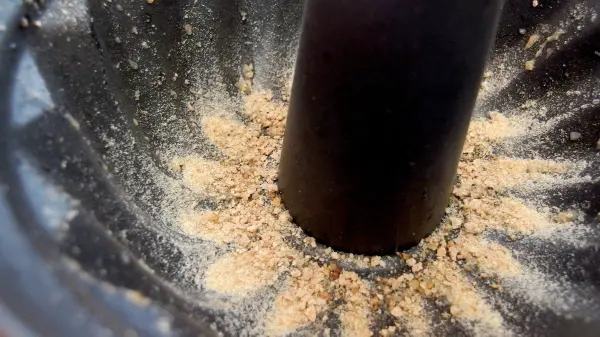 Eine Kuchenform zeigt Krümel, die gleichmäßig um das zentrale Rohr verteilt sind, als Vorbereitung für das Backen.