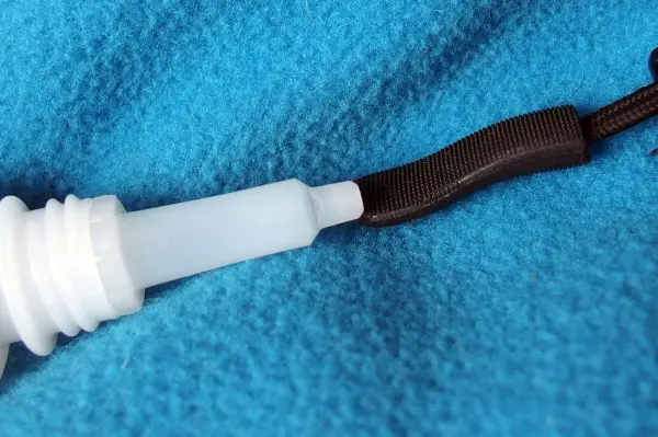 Ein Stoff-Zipper mit einem Bändel, der an einem weißen Verschluss befestigt ist, liegt auf einem blauen Hintergrund.