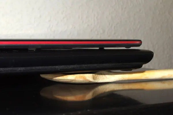 Ein schwarzes Notebook liegt auf einem Holzlöffel, wodurch die zusätzliche Kühlung beim Arbeiten ermöglicht wird.