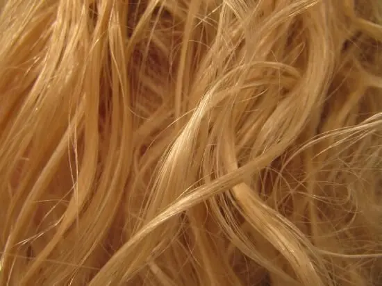 Blonde Haare schimmern im Licht, zeigen seidige, gewellte Strähnen, die nahtlos ineinander verflochten wirken.