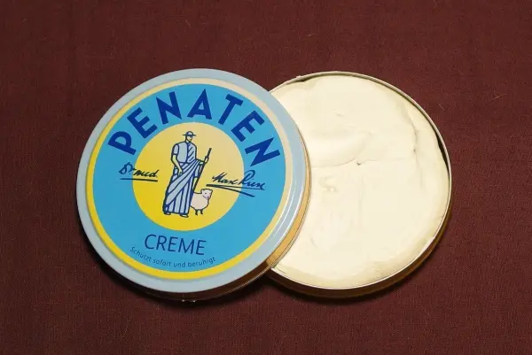Eine runde Dose mit Penatencreme steht offen auf einem braunen Untergrund, bereit zur Anwendung bei kleinen Wunden.