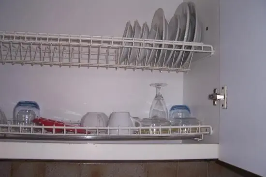 Geschirr trocknet in einem offenen Küchenschrank auf einem Abtropfgestell, während es ordentlich gestapelt ist.