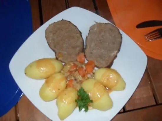 Auf einem Teller liegen zwei Scheiben Falscher Hase (Hackbraten) umgeben von gekochten Kartoffeln und Gemüse.