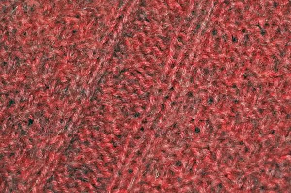 Ein kratzender Wollpullover zeigt eine grobe, rot-braune Textur, die dicht gestrickt und warm wirkt.