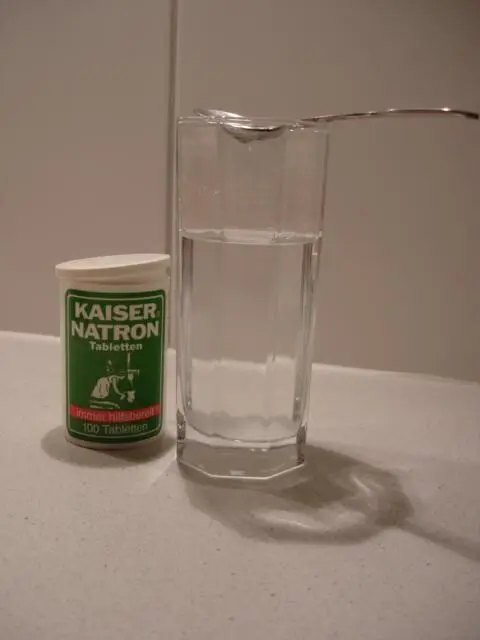 Ein Behälter mit Wasser steht neben einer Dose mit Kaiser Natron, während ein Löffel bereit ist, das Natron hinzuzufügen.