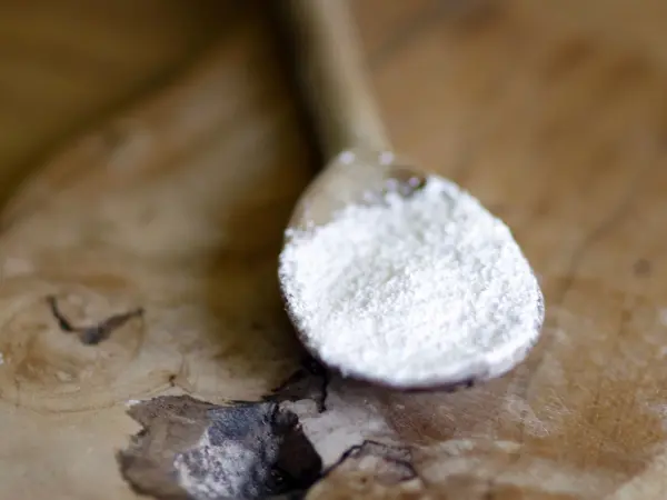 Ein Holzlöffel hält ein wenig Kaiser Natron, während er auf einer rustikalen Holzoberfläche liegt.