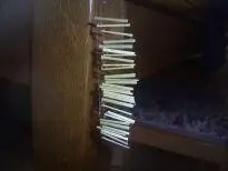Ein Bündel Gräser hängt an einer Holzoberfläche in einem dunklen Raum. Text ist nicht vorhanden.