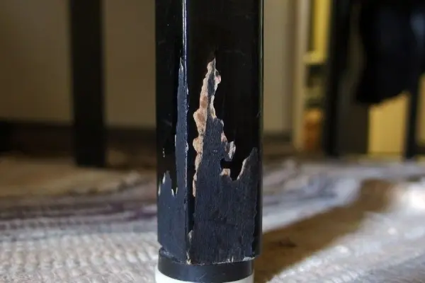 Ein beschädigtes Stuhlbein zeigt Kratzer und Abnutzungsspuren, verursacht durch das Knabbern von Haustieren im Wohnraum.