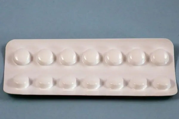 Eine Tablettenblisterpackung zeigt mehrere rundliche Tabletten, die zum Einnehmen bereitliegen auf einem einfarbigen Hintergrund.