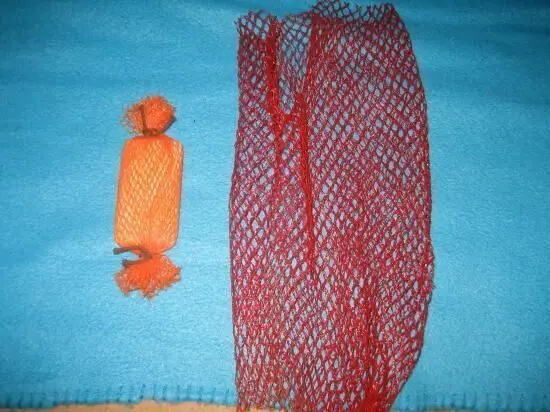 Ein orangefarbener Körper und ein rotes Netz liegen auf einem blauen Stoff, bereit für das Peeling der Haut.