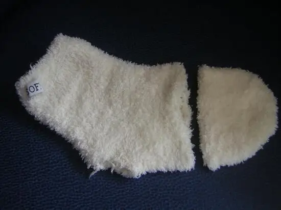 Ein zerlegter weißer Socken liegt auf dunklem Hintergrund. Ein Teil des Socken hat ein Etikett mit der Aufschrift "OF".