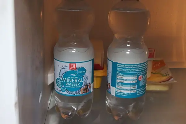Gekühlte Getränkeflaschen stehen nebeneinander in einem Kühlschrank und warten darauf, entnommen zu werden.