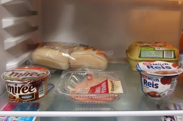 Im Kühlschrank liegen mehrere Lebensmittel wie Joghurt und belegte Brötchen, die möglicherweise vergessen wurden.