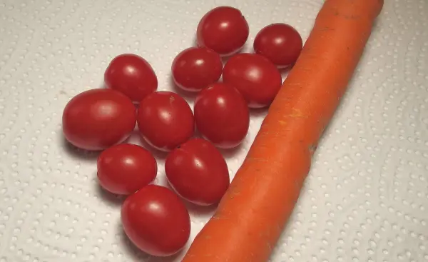 Frische Tomaten und eine Karotte liegen auf einem Küchenpapier, bereit für die Lagerung im Kühlschrank, um Gemüse länger haltbar zu machen.