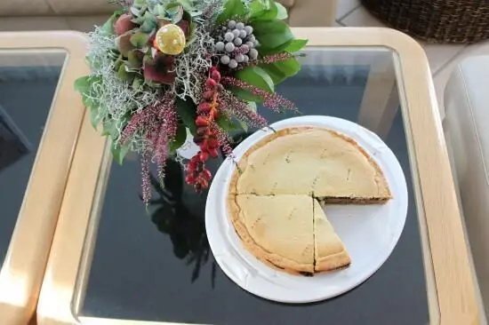 Ein Gedeckter Nusskuchen mit einer Schnittfläche steht auf einem Tisch neben einer dekorativen Blumenarrangement.