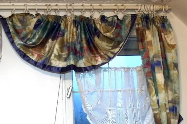 Bunte Gardinen hängen dekorativ am Fenster, bereit zum Waschen in der Waschmaschine, um Frische ins Zimmer zu bringen.