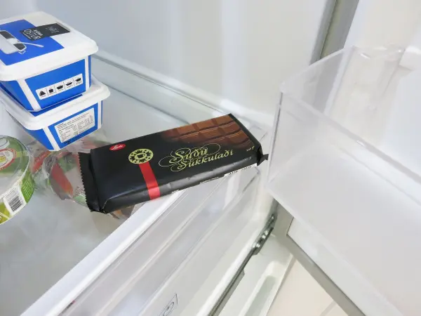 Eine Schokoladentafel liegt in einem Kühlschrank, bereit zum Raspeln mit der Küchenmaschine für ein Rezept.
