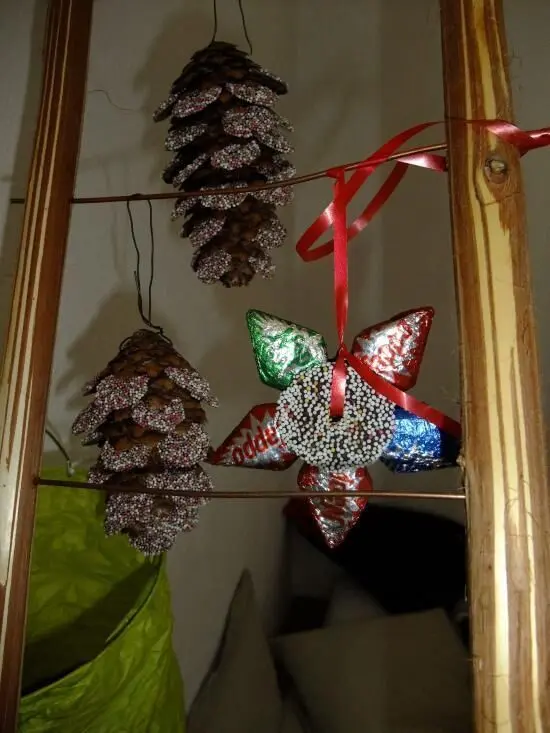 Zweige mit Tannenzapfen und einer bunten, sternförmigen Dekoration sind kreativ zur Vorweihnachtszeit arrangiert.