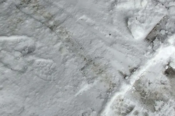 Schnee bedeckt eine Fläche, während Abdrücke darauf sichtbar sind, was eine Reinigung mit Schnee andeutet.