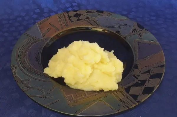 Luftiges Kartoffelpüree liegt auf einem dekorativen Teller, umgeben von einem blauen Hintergrund, der die Farben betont.