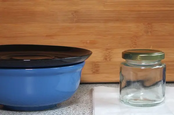 Eine blaue Schüssel und ein leeres Einmachglas stehen auf einer Tischoberfläche, um plastikfreie Alternativen zu zeigen.