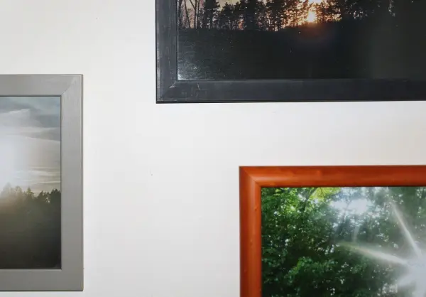 Mehrere Bilder in verschiedenen Rahmen hängen an einer hellen Wand, ohne dass sie verrutschen, dank Radiergummi-Resten.