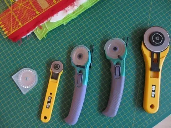 Vier Rollschneider liegen auf einem grünen Schneidemattenuntergrund, bereit, Papier präzise zu schneiden.