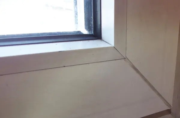 Weiße Fensterrahmen zeigen Rückstände. Backofenspray wird aufgetragen, um die Reinigung im Innenraum zu erleichtern.