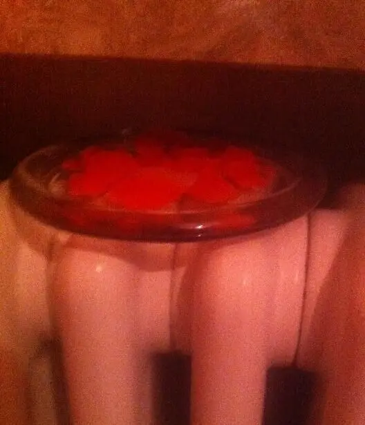 Ein Glas mit geschmolzenem Wachs von Duftkerzen steht auf einer Heizung und kühlt in einer warmen Umgebung ab.