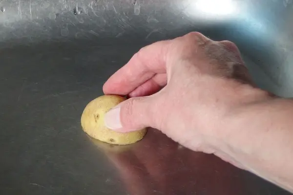 Eine Hand reinigt mit einer halben Zitrone eine Edelstahlspüle, um frischen Glanz zu erzielen.
