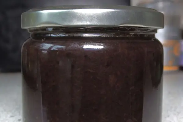 Ein Einmachglas mit dunkler Marmelade steht auf einer Arbeitsfläche, bereit zum Einfrieren der Gerichte.