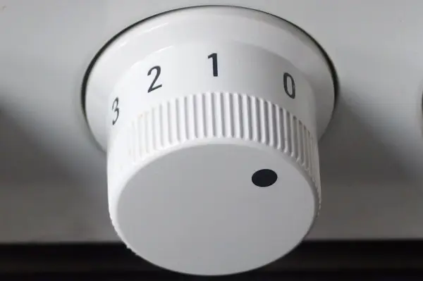 Ein weißer Drehknopf mit Zahlen von 0 bis 3 wird zur Regelung der Temperatur genutzt, um Energie zu sparen.
