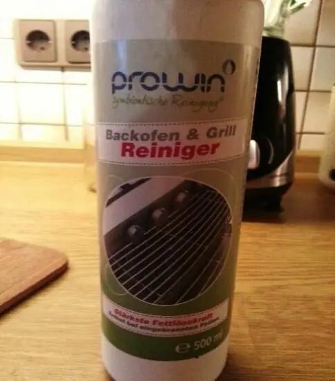 Reinigerflasche steht auf der Küchenarbeitsplatte, zeigt Bild eines Grillrosts. Text: "prowin symbiontische Reinigung, Backofen & Grill Reiniger, Stärkste Fettlösekraft".