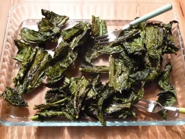 In einer Glasschale liegen knusprige Chips aus Schwarzkohl, die appetitlich gebräunt und knusprig sind.