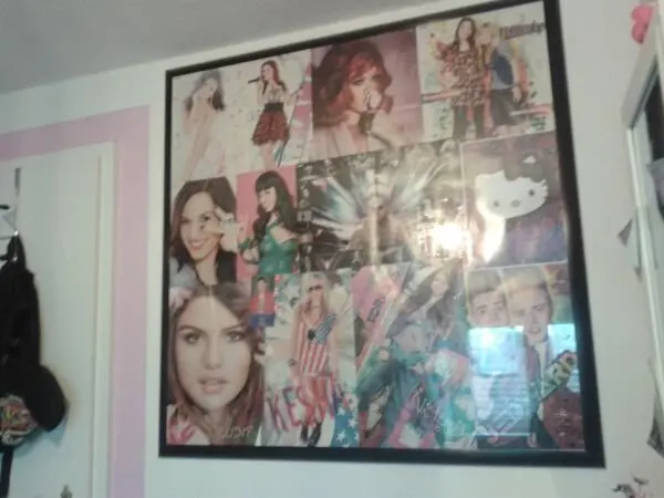 Ein großformatiger Bilderrahmen zeigt ein Collage-Poster mit verschiedenen Porträts und Models an einer Wand im Zimmer.