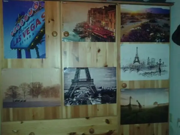 Diverse Poster im Bilderrahmen schmücken eine Holzpaneelwand, die stimmungsvolle Städte und Wahrzeichen zeigt.